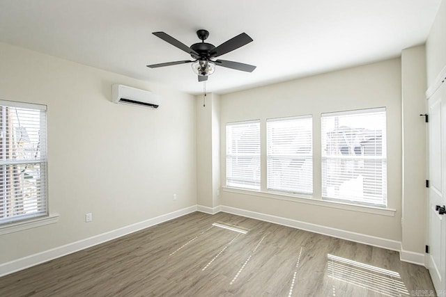 spare room featuring ceiling fan, baseboards, wood finished floors, and a wall mounted AC