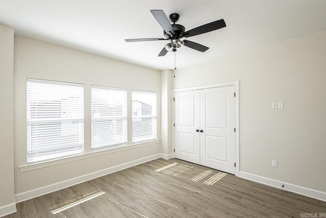 spare room with wood finished floors, a ceiling fan, and baseboards