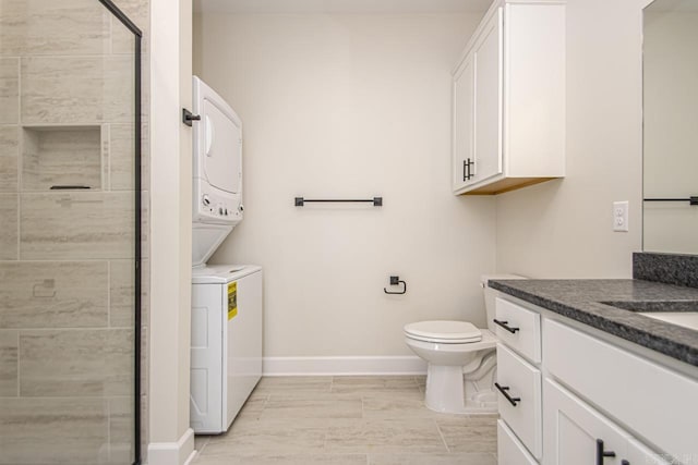 bathroom with toilet, vanity, baseboards, stacked washing maching and dryer, and a shower stall