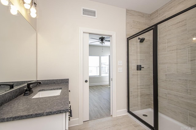 bathroom featuring ceiling fan with notable chandelier, vanity, visible vents, baseboards, and a stall shower