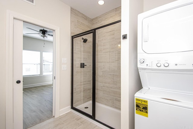 full bathroom with a stall shower, baseboards, a ceiling fan, and stacked washer and clothes dryer