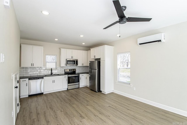 kitchen featuring a sink, appliances with stainless steel finishes, a wall mounted AC, tasteful backsplash, and dark countertops