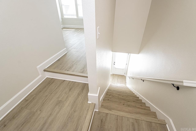 stairs with wood finished floors and baseboards