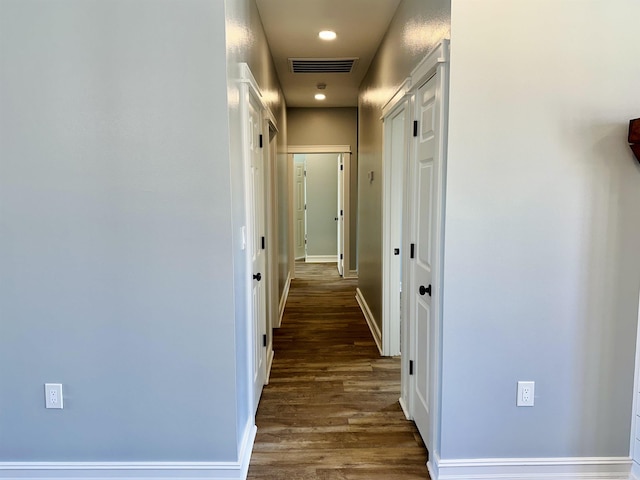 hallway with wood finished floors, visible vents, and baseboards