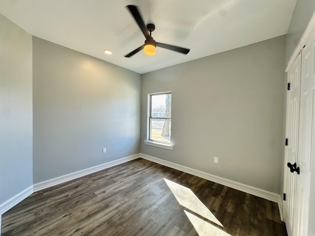 unfurnished bedroom featuring dark wood-type flooring, a closet, ceiling fan, and baseboards