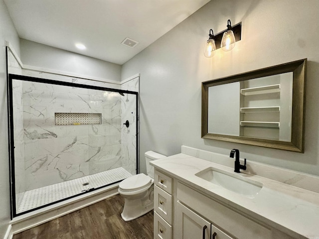 bathroom featuring a marble finish shower, visible vents, toilet, vanity, and wood finished floors