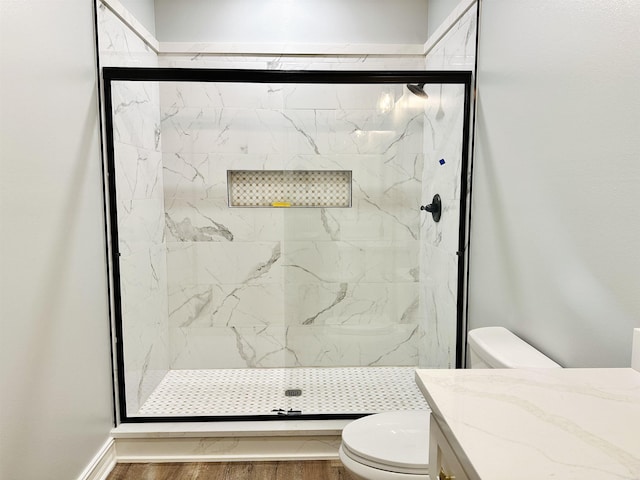 full bath with a marble finish shower, vanity, toilet, and wood finished floors