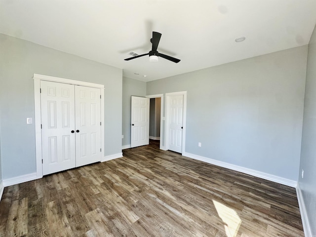 unfurnished bedroom with a closet, wood finished floors, a ceiling fan, and baseboards