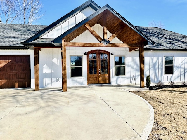 doorway to property featuring a garage, a shingled roof, and board and batten siding