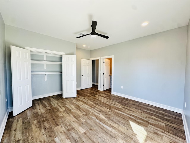 unfurnished bedroom with a closet, recessed lighting, wood finished floors, and baseboards