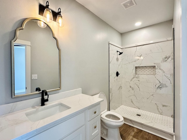 bathroom featuring toilet, wood finished floors, vanity, visible vents, and a stall shower