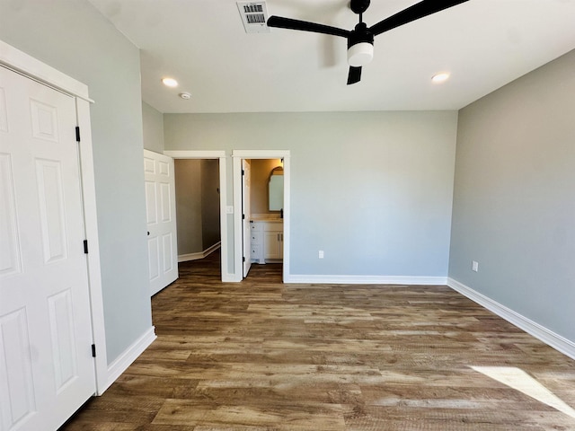 unfurnished bedroom with visible vents, ensuite bathroom, baseboards, and wood finished floors