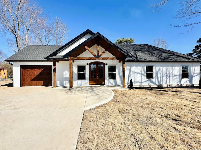 modern farmhouse style home featuring french doors, roof with shingles, board and batten siding, a garage, and driveway