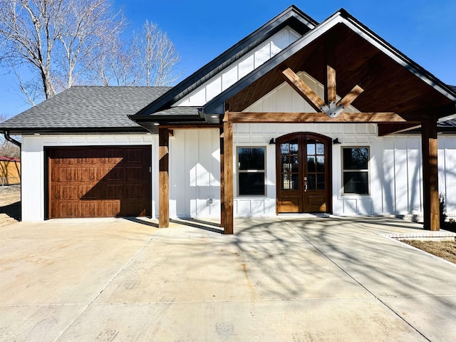 view of front of house with a garage, driveway, roof with shingles, and french doors