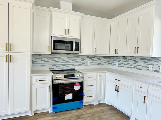 kitchen with stainless steel appliances, white cabinetry, light wood-style floors, light countertops, and backsplash