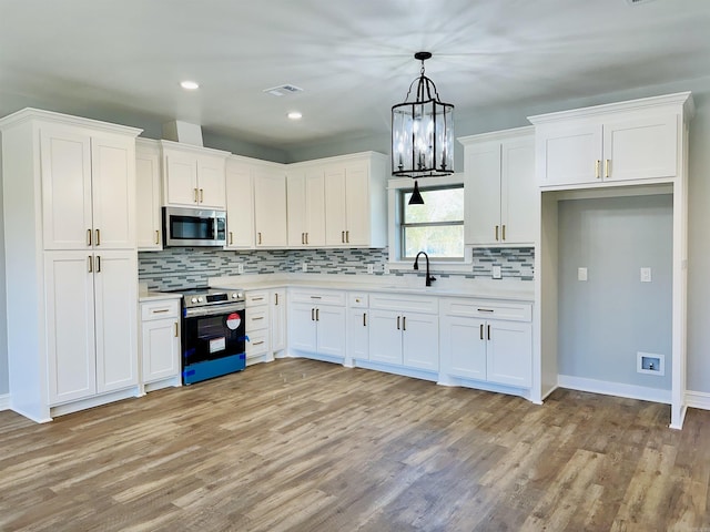 kitchen with visible vents, white cabinets, stainless steel appliances, light countertops, and a sink