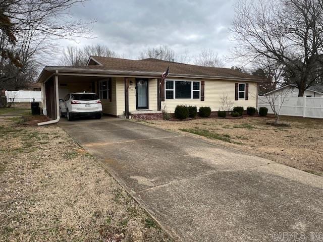 ranch-style house featuring a carport, brick siding, fence, and driveway