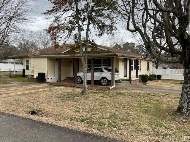 view of front of house featuring an attached carport, fence, driveway, and a front lawn