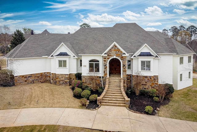 view of front facade featuring a standing seam roof, stone siding, metal roof, and roof with shingles