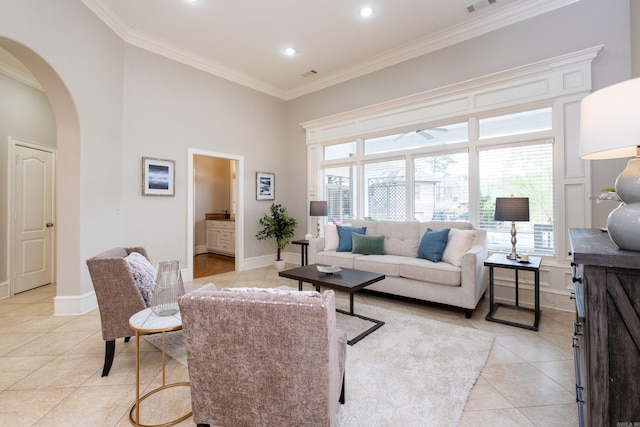 living area with light tile patterned floors, baseboards, arched walkways, a towering ceiling, and ornamental molding