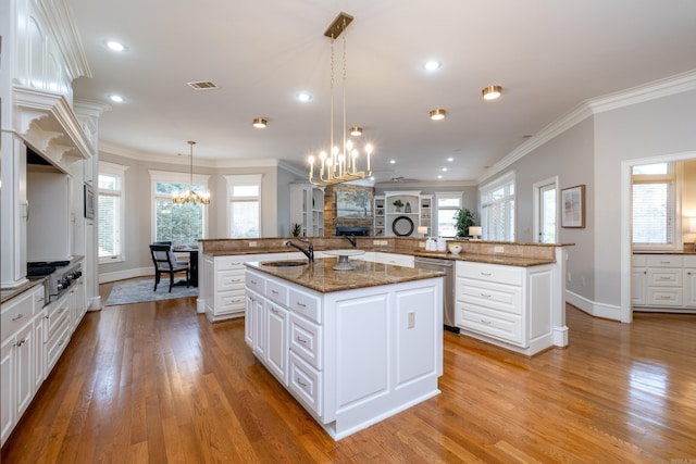 kitchen with appliances with stainless steel finishes, crown molding, a large island with sink, a chandelier, and a sink