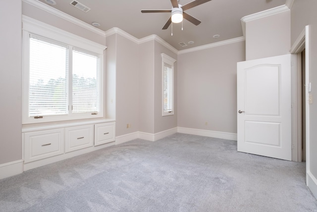 spare room with baseboards, light colored carpet, visible vents, and crown molding