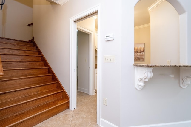 stairway featuring arched walkways, ornamental molding, and tile patterned floors