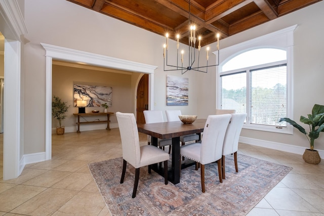 dining space featuring baseboards, arched walkways, coffered ceiling, beam ceiling, and light tile patterned flooring