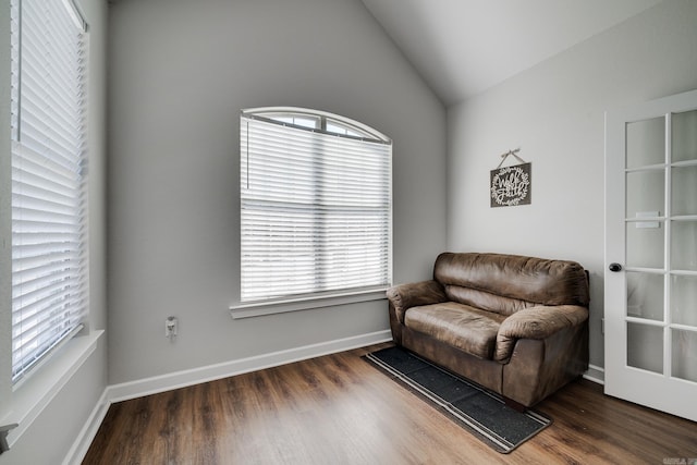 living area featuring baseboards, vaulted ceiling, and wood finished floors