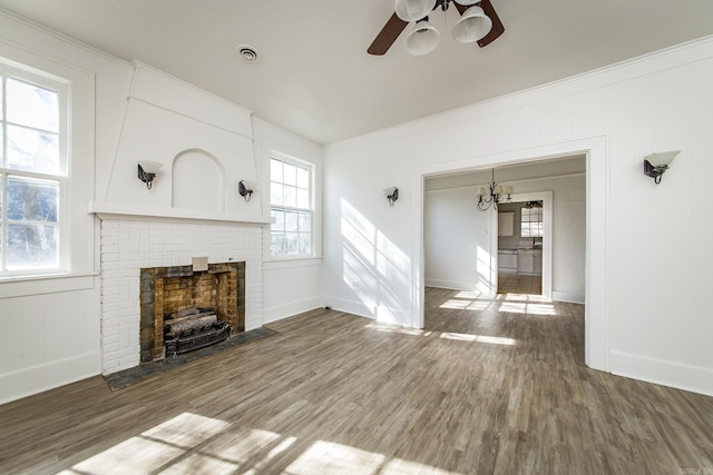 unfurnished living room featuring visible vents, ornamental molding, a brick fireplace, ceiling fan, and wood finished floors