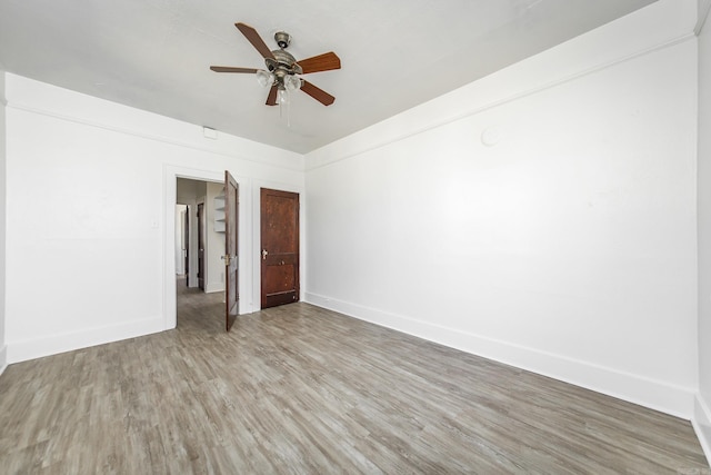 spare room with light wood-type flooring, ceiling fan, and baseboards