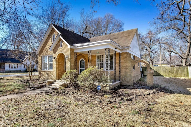 view of front of home with fence, a porch, and brick siding