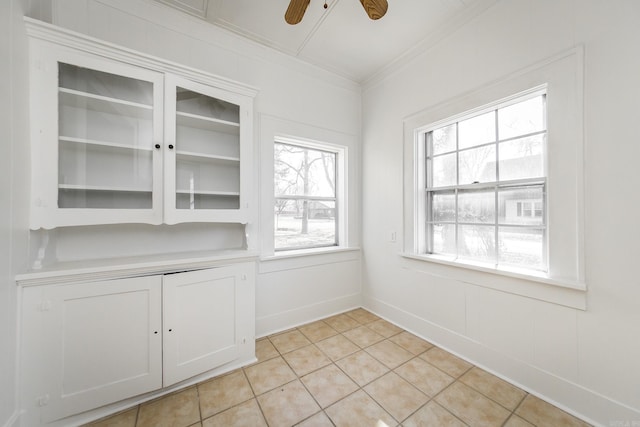interior space featuring ceiling fan, ornamental molding, light tile patterned flooring, and baseboards