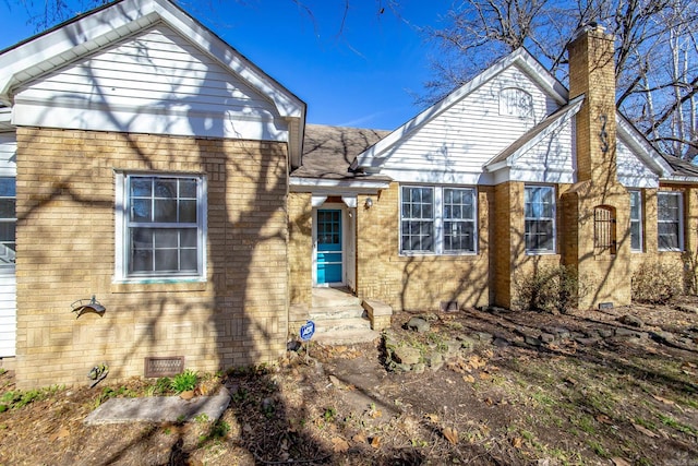 view of front of house featuring crawl space, brick siding, and a chimney