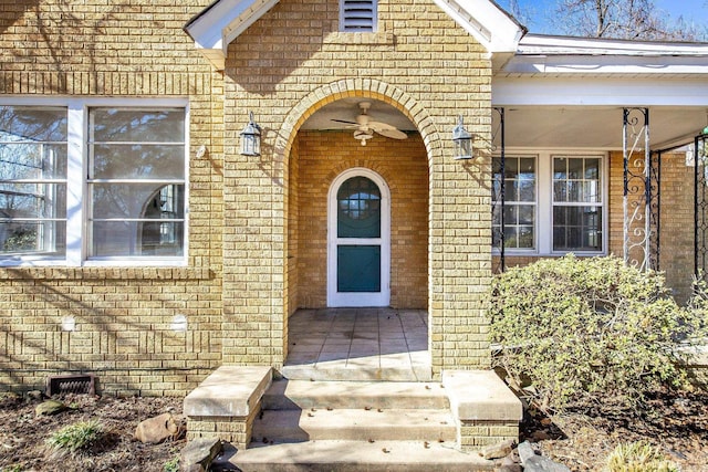 view of exterior entry with brick siding and a porch