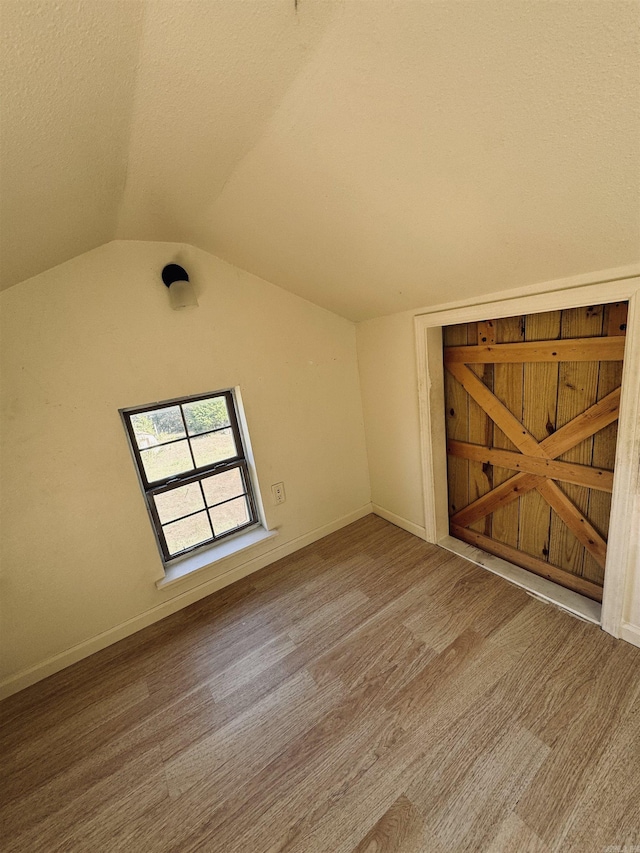 interior space featuring lofted ceiling, baseboards, and wood finished floors