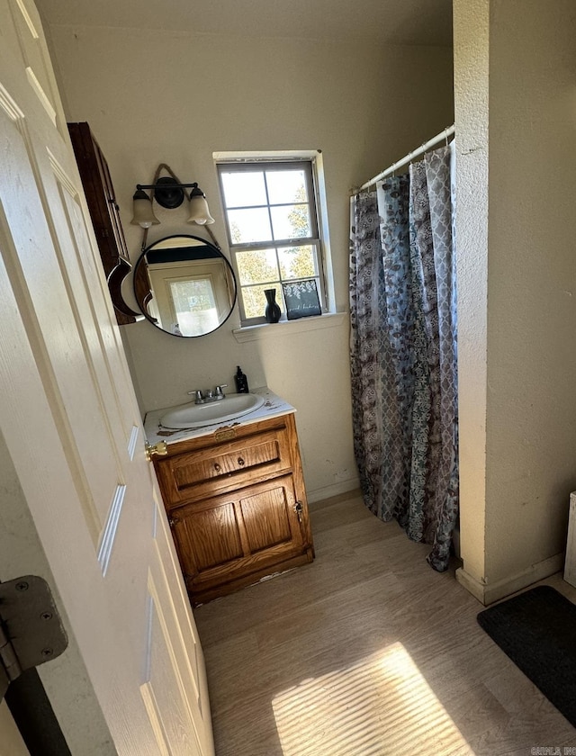 bathroom with curtained shower, vanity, and wood finished floors