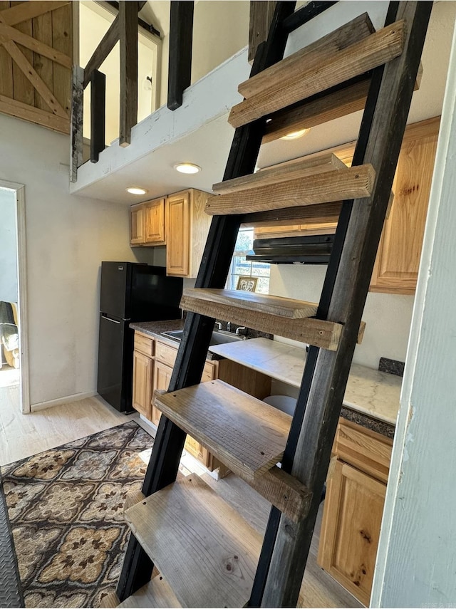 kitchen featuring baseboards, a towering ceiling, freestanding refrigerator, light wood-style floors, and light brown cabinets