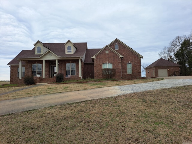 view of front of house featuring a garage, a front yard, brick siding, and an outdoor structure