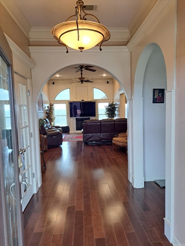 hallway with arched walkways, dark wood-type flooring, and ornamental molding