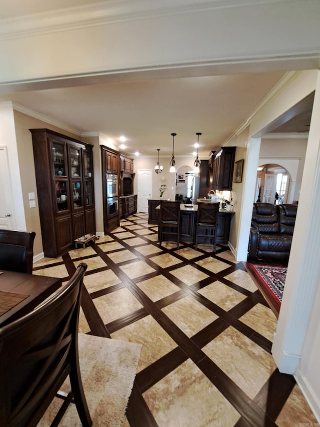 living room featuring baseboards, arched walkways, and ornamental molding