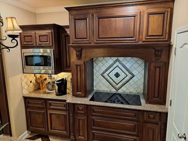 kitchen featuring dark brown cabinetry, decorative backsplash, stainless steel microwave, ornamental molding, and black electric cooktop