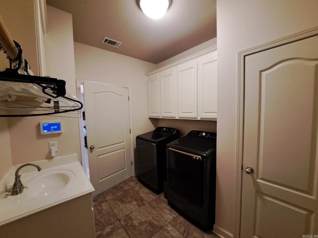 laundry room with cabinet space, washing machine and dryer, visible vents, and a sink