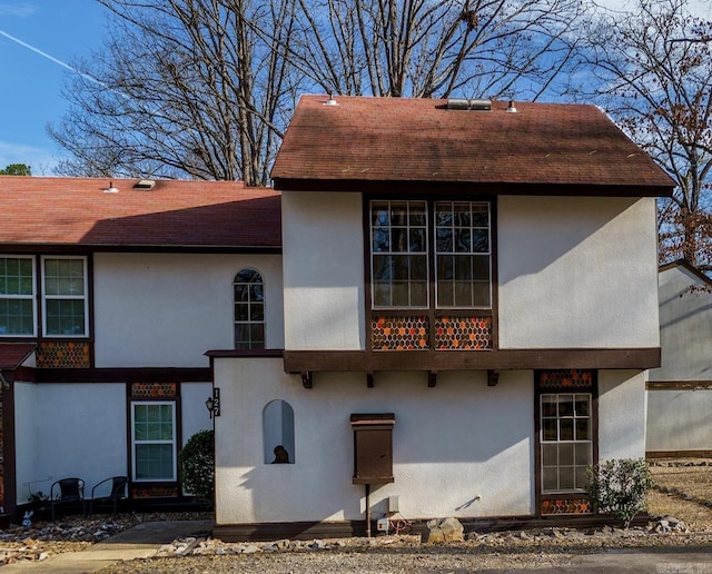 exterior space with a shingled roof and stucco siding