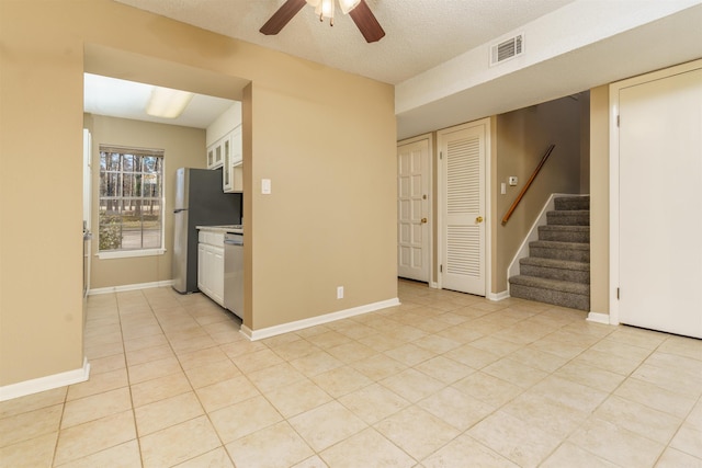 interior space featuring visible vents, baseboards, stainless steel appliances, white cabinetry, and light tile patterned flooring