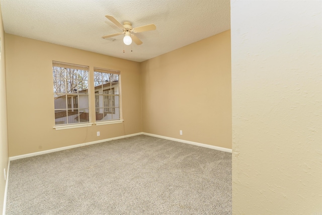 carpeted empty room with a textured ceiling, ceiling fan, and baseboards