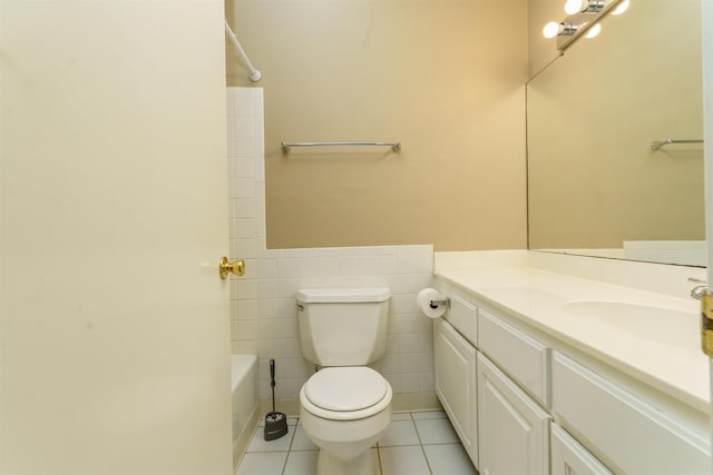 bathroom featuring a wainscoted wall, tile walls, toilet, vanity, and tile patterned flooring