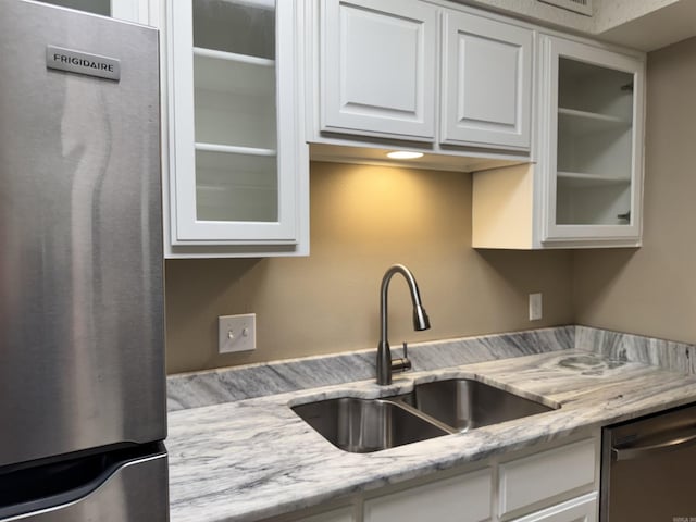 127 Emperado Way, Hot Springs Village, AR 71909 - kitchen featuring appliances with stainless steel finishes, a sink, white cabinetry, glass insert cabinets, and light stone counters