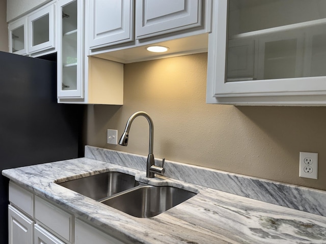 127 Emperado Way, Hot Springs Village, AR 71909 - kitchen with a sink, glass insert cabinets, light stone countertops, white cabinetry, and freestanding refrigerator