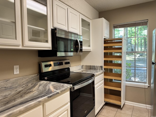 127 Emperado Way, Hot Springs Village, AR 71909 - kitchen with stainless steel appliances, white cabinets, glass insert cabinets, light tile patterned flooring, and light countertops
